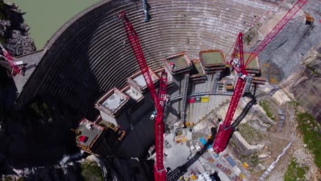 Aerial-drone-top-down-shot-over-dam-under-construction-beside-Hotel-Grimsel-Hospiz-along-Grimsel-Pass,-Swiss-Mountain-in-Switzerland-on-a-sunny-day