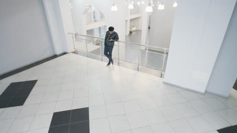 man standing on a balcony in a modern building using a phone