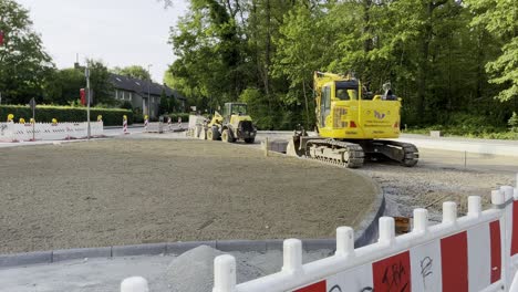 Road-construction-site-with-barrier-and-excavator-where-new-pavement-and-path-boundaries-are-being-built