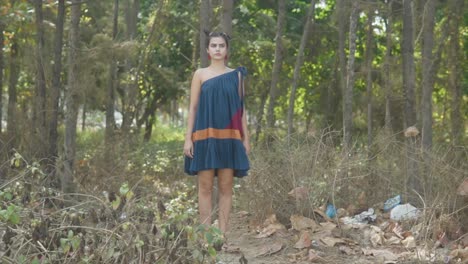 a woman in a dark blue dress standing in a woodland area