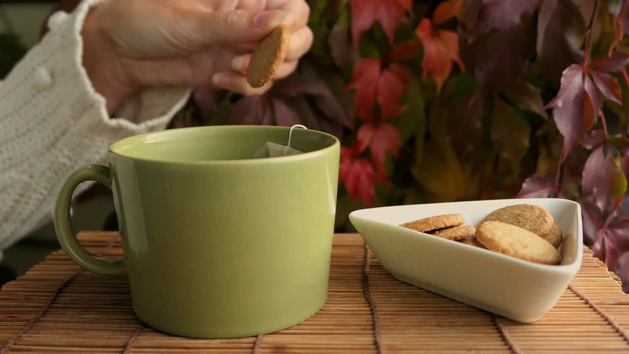 mujer disfrutando de galletas y té, taza de té y galletas en la mesa en otoño
