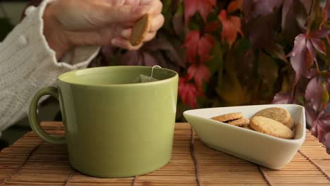 Mujer-Disfrutando-De-Galletas-Y-Té,-Taza-De-Té-Y-Galletas-En-La-Mesa-En-Otoño