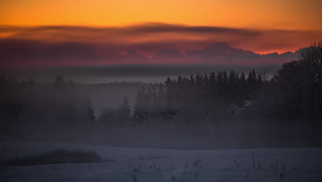 time lapse shot of frosty and snowy fields and spruce trees during golden sunset with flying clouds in background - beautiful winter scene in the evening
