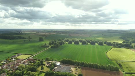 high drone view of british countryside with historical buildings and green fields for miles on bright but cloudy day