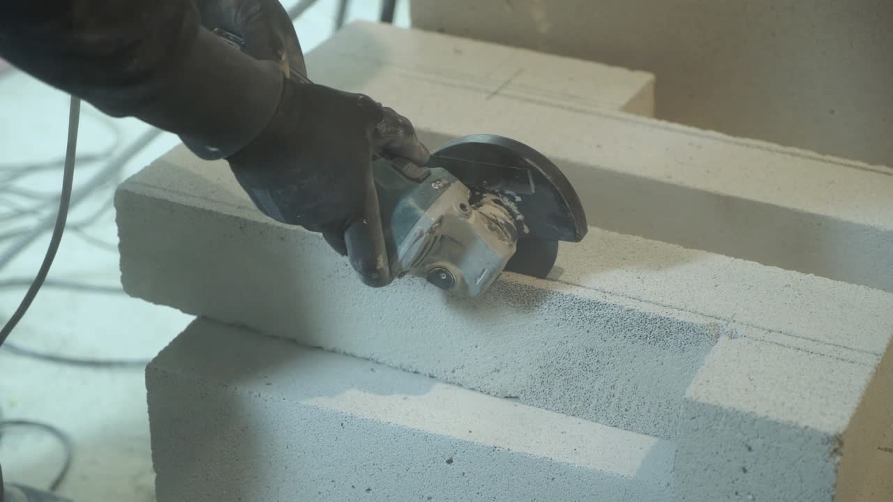 closeup of builder sawing aerated concrete block with circular saw