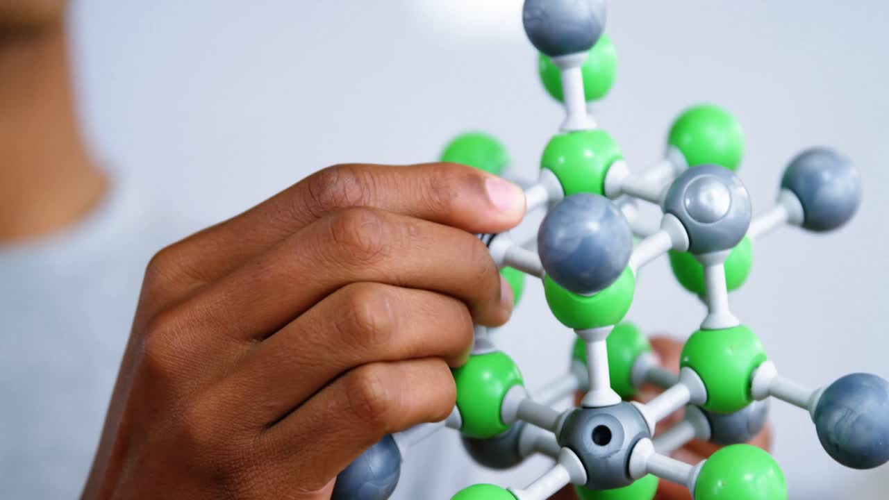 escolar experimentando con un modelo de molécula en el laboratorio de la escuela