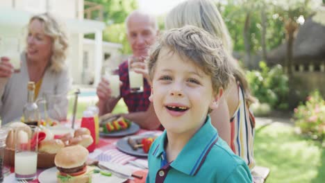 Porträt-Eines-Glücklichen-Kaukasischen-Jungen,-Der-Mit-Der-Familie-Im-Garten-Zu-Abend-Isst