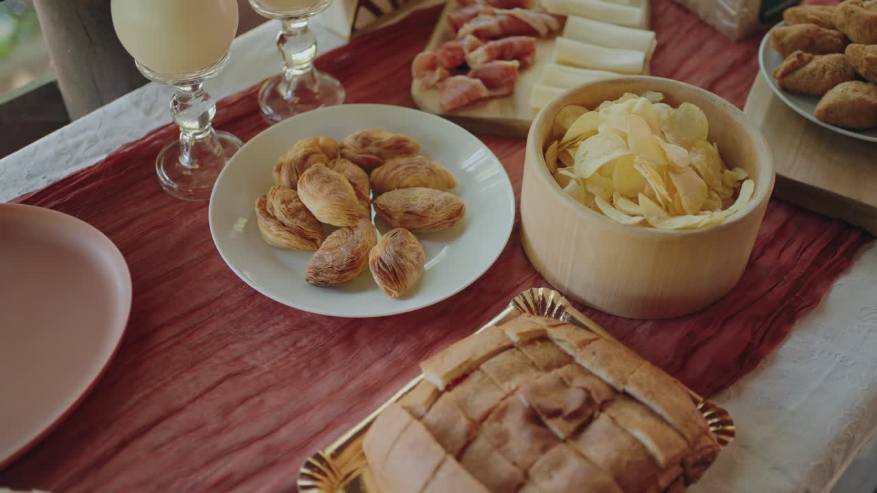 Variety of appetizers including bread, pastries, cheese and chips on rustic table
