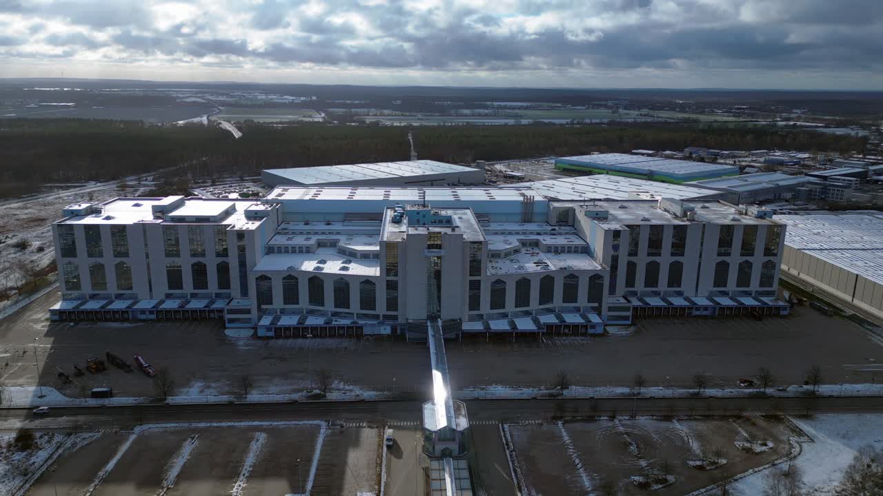 Large distribution center with loading docks and parking lot under a cloudy sky in winter. Marvelous aerial view flight drone shot footage from above