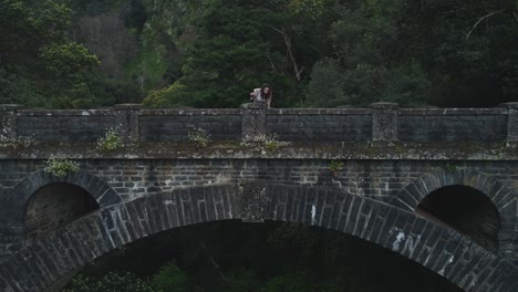 drone view of woman standing on old bridge in madeira, portugal