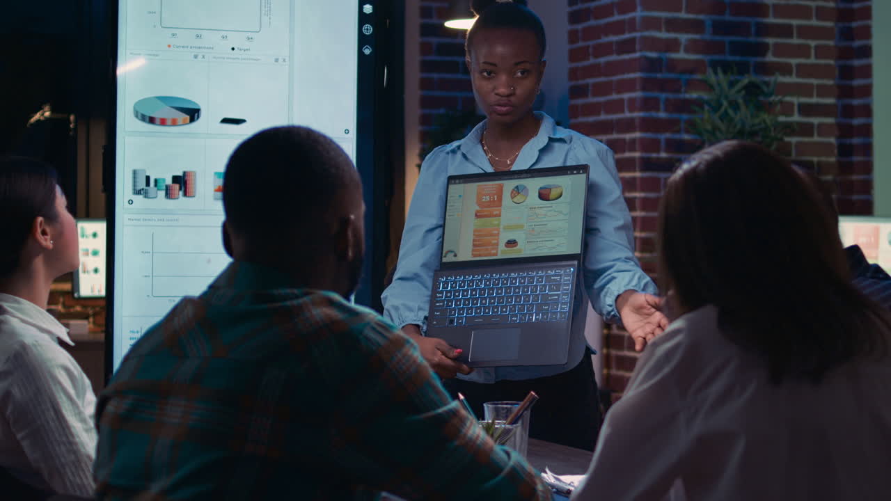 Employee presenting financial report, showing charts on laptop screen