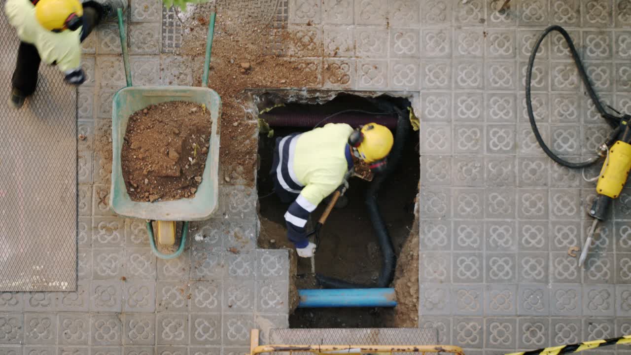 primer plano de vista superior del trabajador constructor cavando paleando y rompiendo un hormigón en una calle de barcelona
