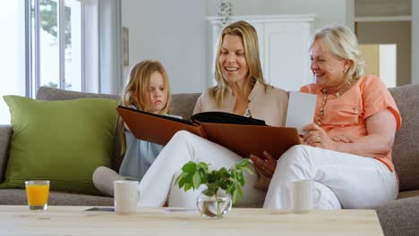 multi-generation family looking at photo album in living room 4k