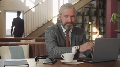 portrait of senior businessman with laptop in restaurant