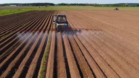 farmer on a tractor sprays plowed fields with fertilizers and chemicals