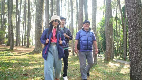 fotografía de seguimiento de una familia asiática caminando por un sendero en un bosque durante unas vacaciones de campamento