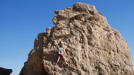 man rock climbing a cliff near the ocean