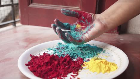 Handspiel-Mit-Farbigen-Pulvern-Vom-Teller-Auf-Holi,-Indisches-Fest-Zu-Hause-Wegen-Covid-19-sperrung,-Zeitlupe