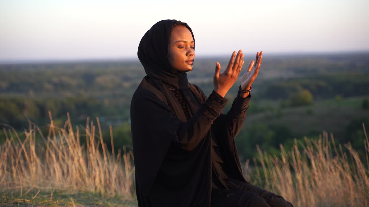 4k Donna musulmana nera che prega sul tappeto. Preghiera Solat sulla splendida collina. Preghiera tradizionale Salah.