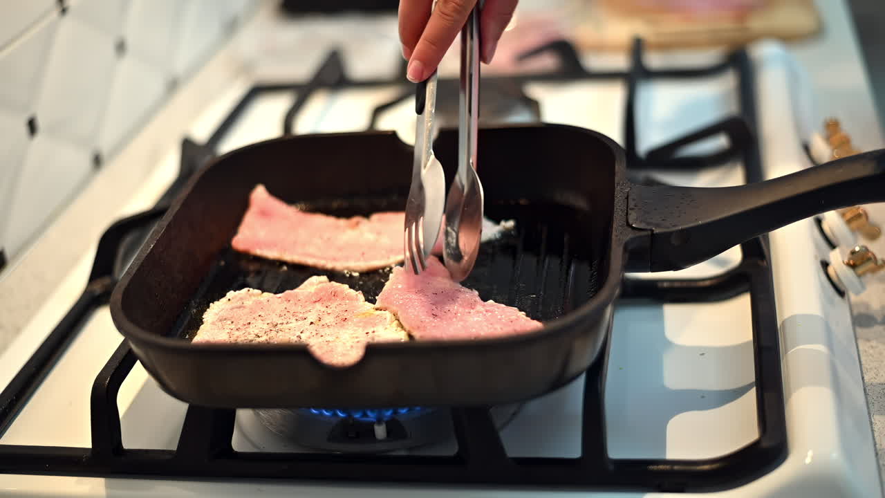 Sizzling bacon cooks in a skillet on a gas stove. A chef skillfully flips the strips, enhancing their golden color and rich flavor. Breakfast is almost ready