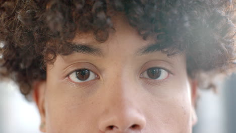 close-up of young person's eyes with curly hair, looking directly at camera