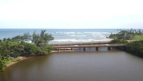 Aerial-view-passing-over-bridge-over-estuary-and-towards-sea