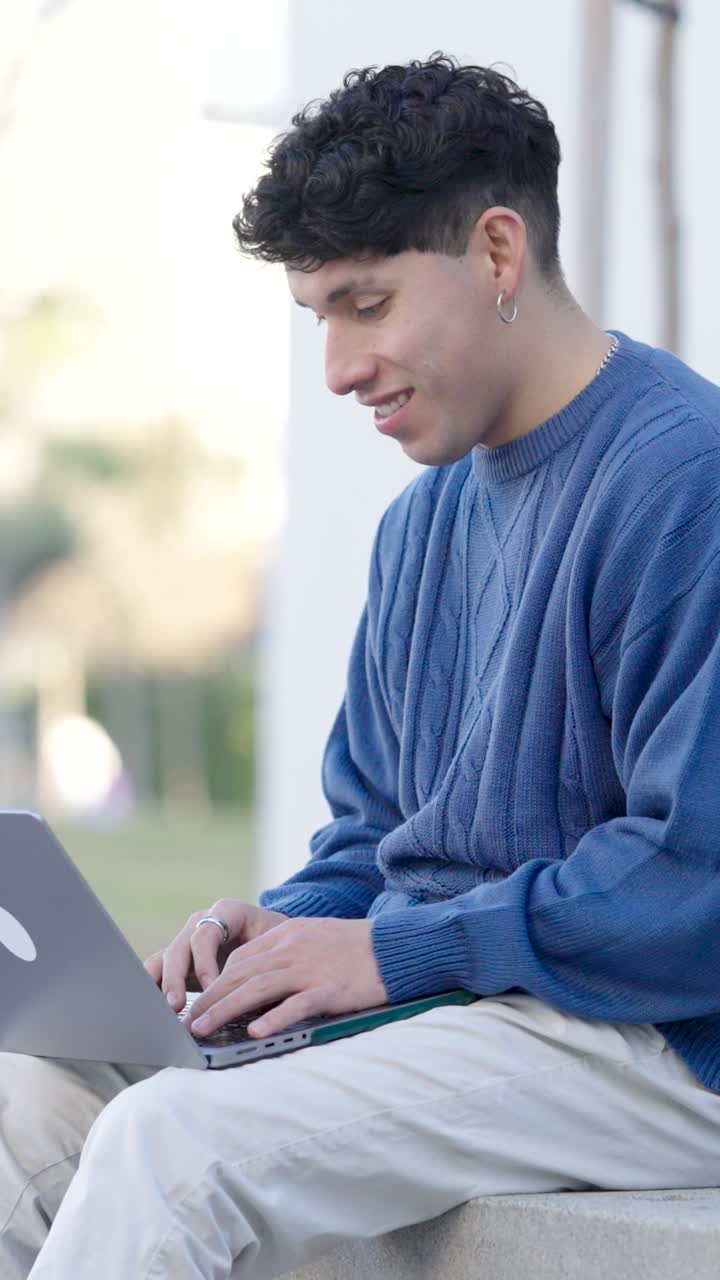 Young student working on laptop outdoors. Vertical