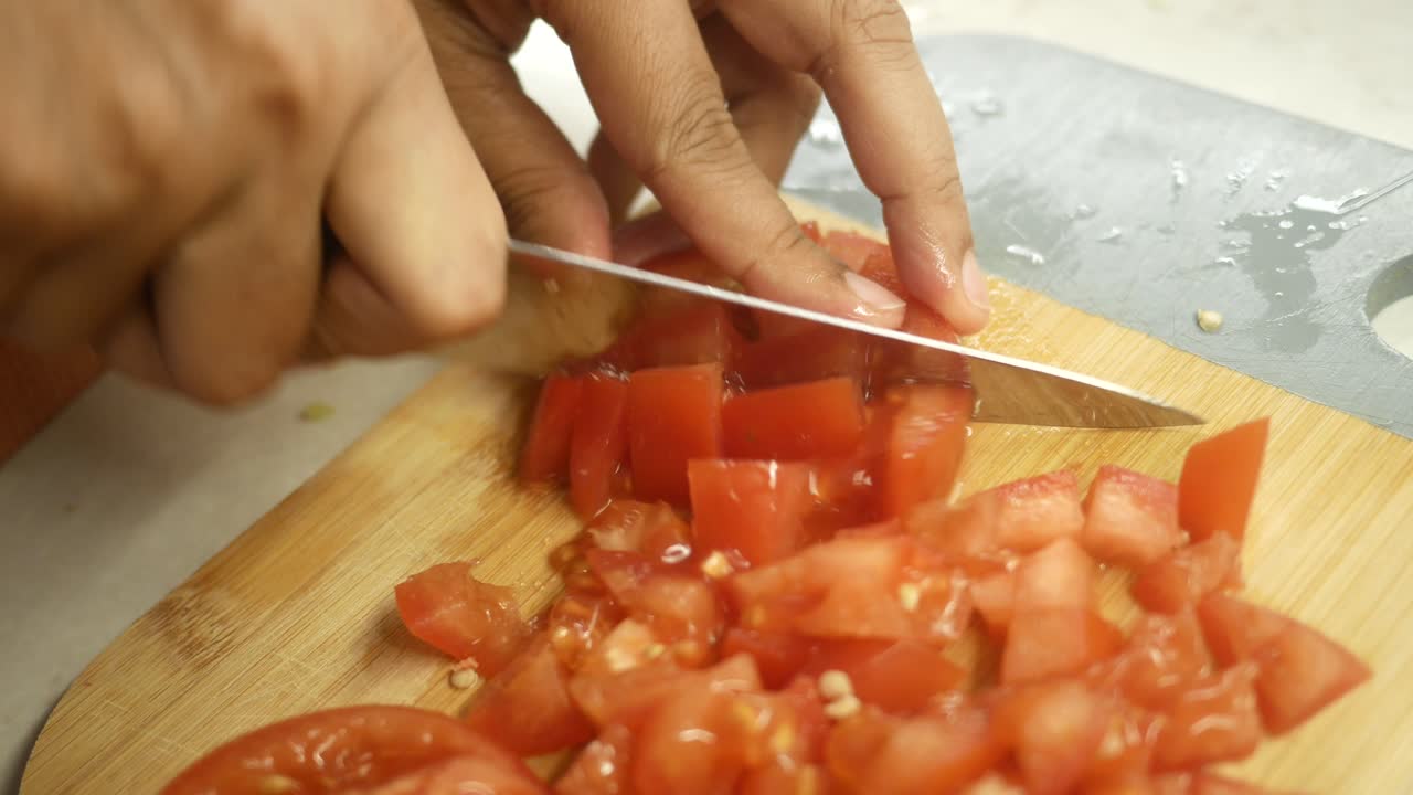 un primer plano de alguien cortando tomates en una tabla de cortar de madera.