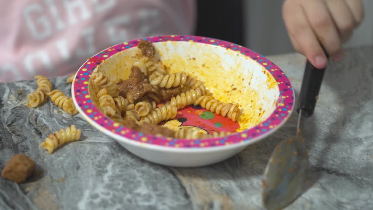 primer plano de un plato colorido con pasta y salsa, rodeado de comida derramada en la mesa
