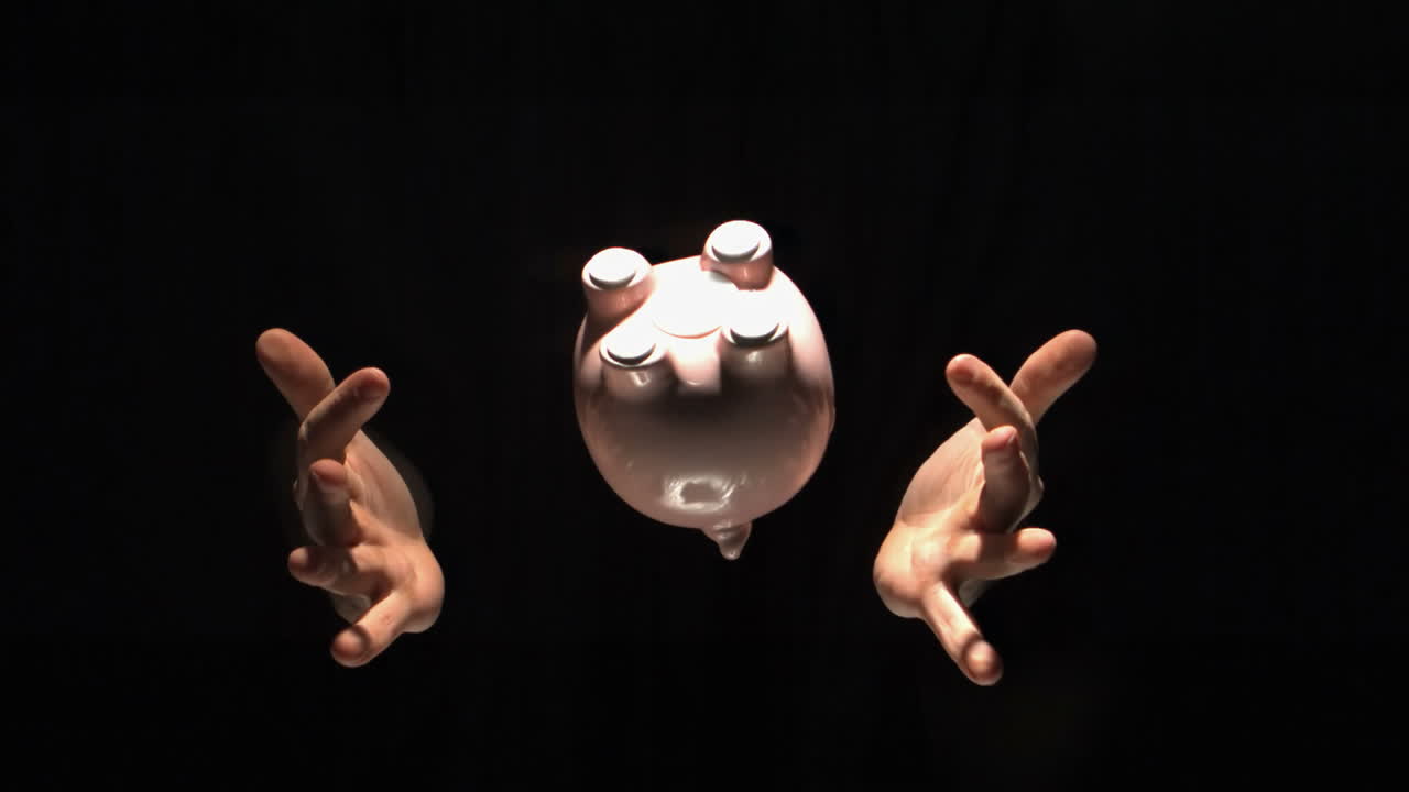 남자의 손은 분홍색 돼지 은행을 던집니다.