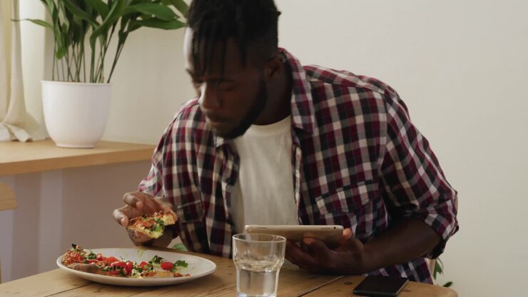 Man eating at home and using tablet