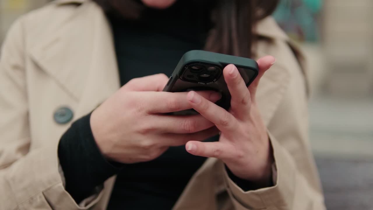 Primo piano delle mani di una donna che usa uno smartphone all'aperto