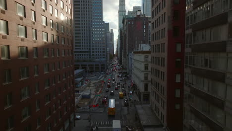 Aerial-tracking-traffic-on-Broadway-street.-One-way-road-between-high-rise-downtown-buildings.-Manhattan,-New-York-City,-USA