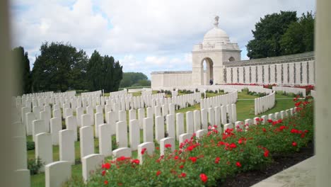 headstones at a war memorial cemetery amongst a beautiful green garden with red roses in ypres beglium, sliding handheld shot