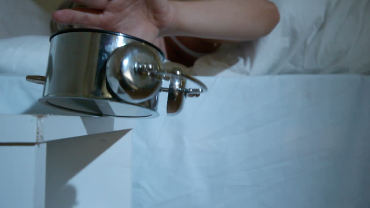 침대에서 금발 여자 알람 시계를 두드리는