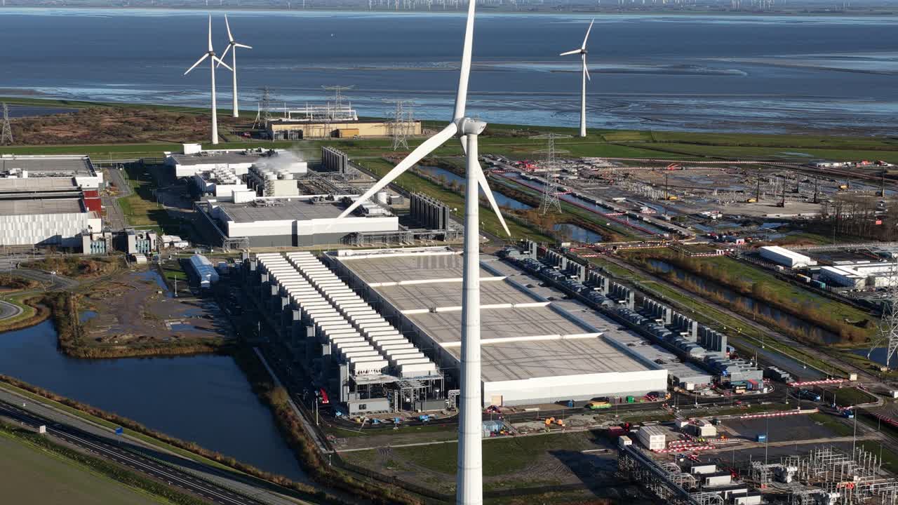 Aerial drone video of wind turbines powering a massive hyperscale data center, showcasing renewable energy sources for the huge consumption of modern IT infrastructure