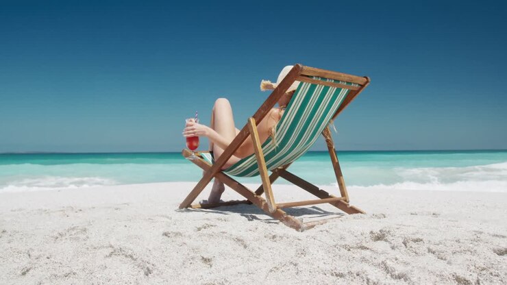 Donna che beve un cocktail su una sdraio sulla spiaggia