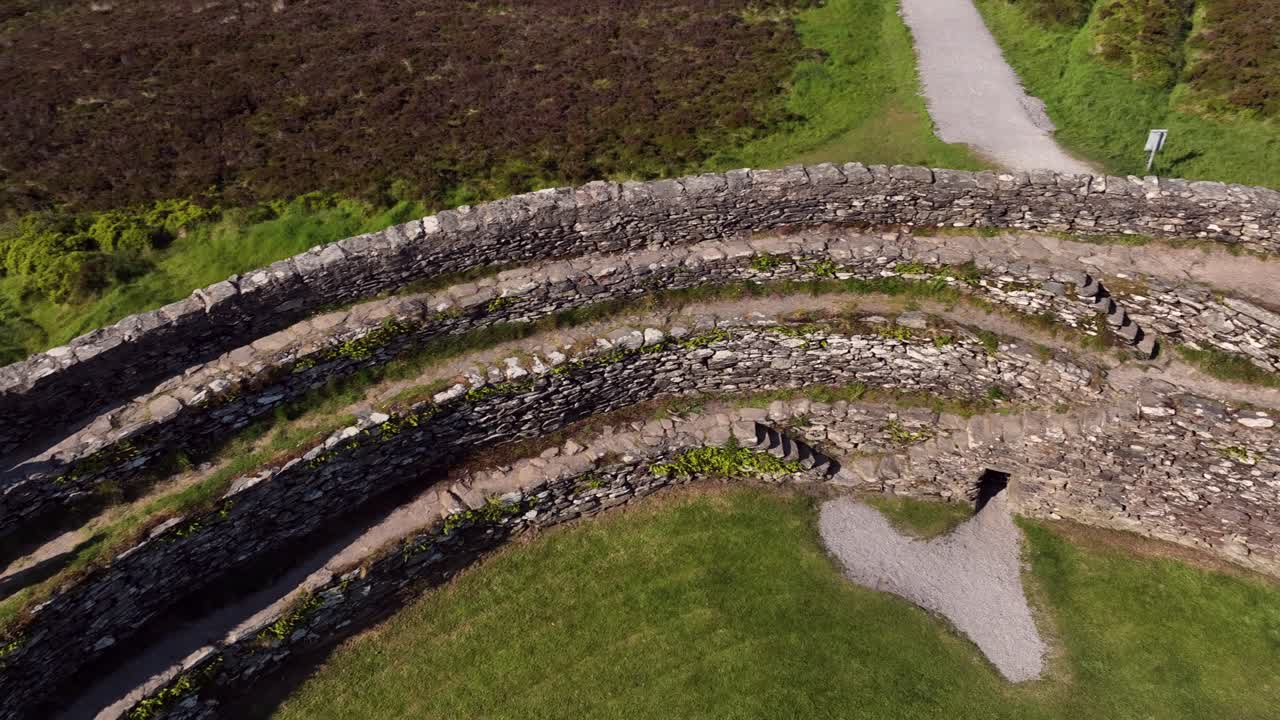 Grianan of Aileach, County Donegal, Ireland, June 2023. Drone pans left revealing the interior of stone ringort with green grass, stone steps and the rugged structure of the historic monument.