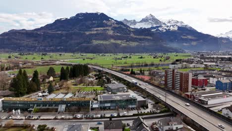autopista ocupada en la idílica ciudad suiza y cordillera con pico nevado en el fondo