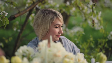 Retrato-De-Una-Mujer-Adulta-En-Un-Jardín-Floreciente-En-La-Primavera-La-Dama-Está-Sentada-En-La-Mesa-De-Una-Fiesta-Familiar-Y-De-Amigos