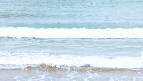 Gentle waves roll onto the sandy beach at Port Campbell, Australia. The serene ocean scene captures the rhythmic motion of the sea