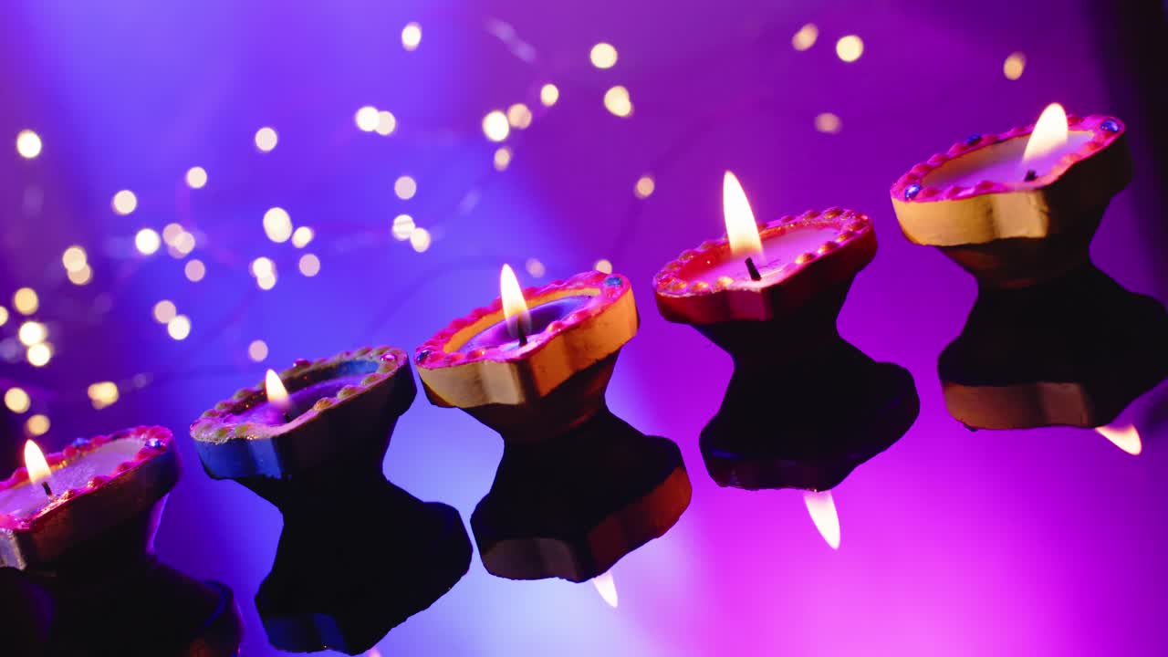 cerca de las luces y la quema de velas de colores celebrando diwali sobre un fondo púrpura