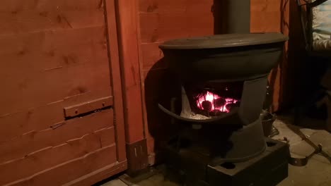 cast iron wood burning stove blazing in outdoor wooden cabin kitchen