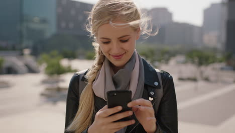 slow motion portrait of cute young blonde woman texting browsing using smartphone social media app in windy urban city background