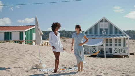 amigas sonrientes bailando en la playa en casas a la orilla del mar. una pareja lgbt feliz descansando