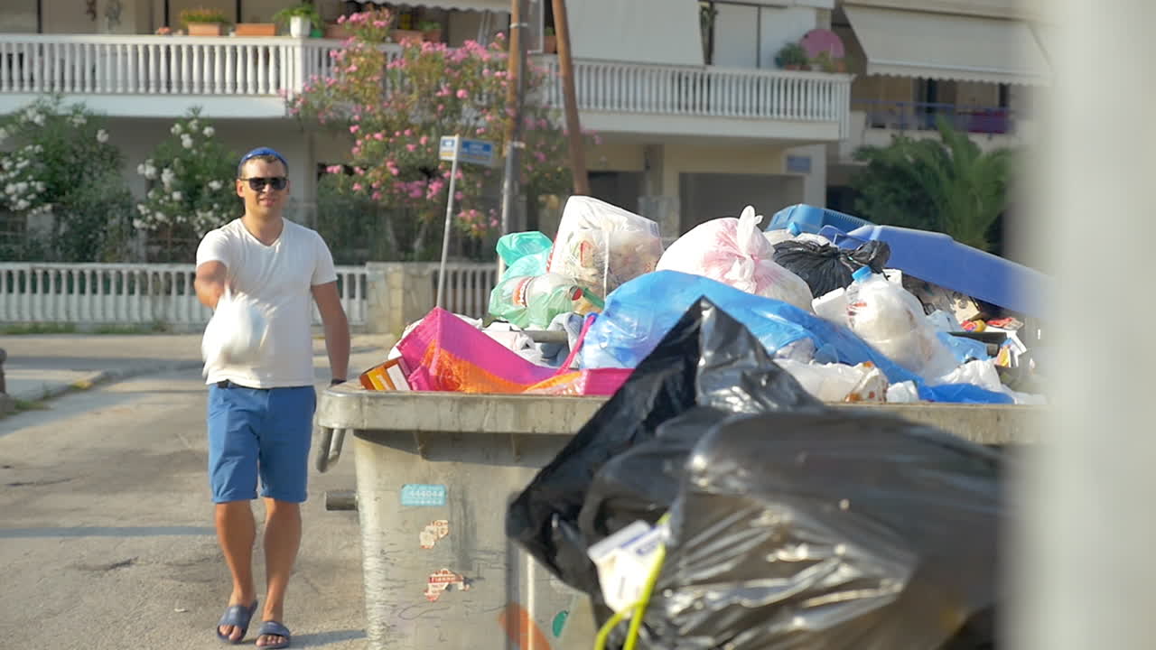 hombre arrojando un paquete de basura al contenedor
