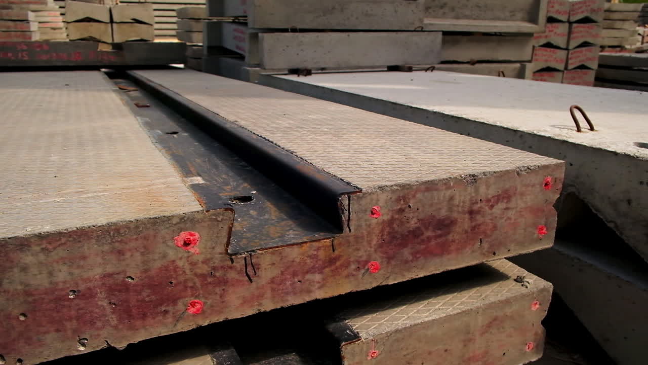 Massive concrete plate with metal rail inside. Close up. Multiple cement materials stacked at background.