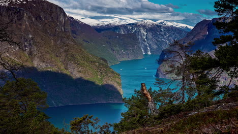 Zeitrafferaufnahme-Aus-Einem-Hohen-Winkel-über-Dem-See-Im-Tal-Mit-Schneebedeckter-Bergkette-Rundherum-In-Flam,-Norwegen,-An-Einem-Bewölkten-Tag