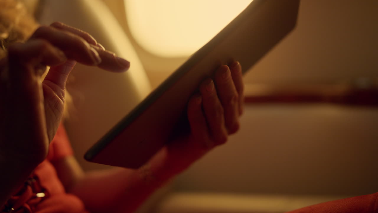 Successful lady holding tablet at airplane window. Hand touch pad screen closeup