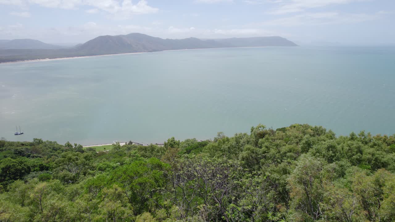 persona agitando la mano en un dron, de pie en el mirador de la colina cubierta de hierba con un faro en cooktown, queensland, australia